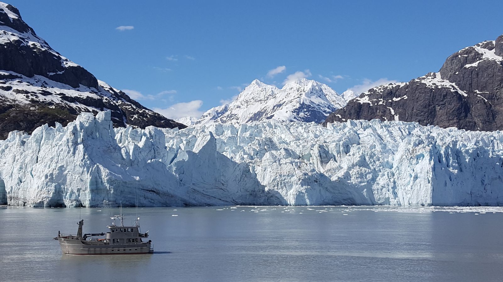 Small ship in front of a tidewater glacier on an expedition cruise in Alaska