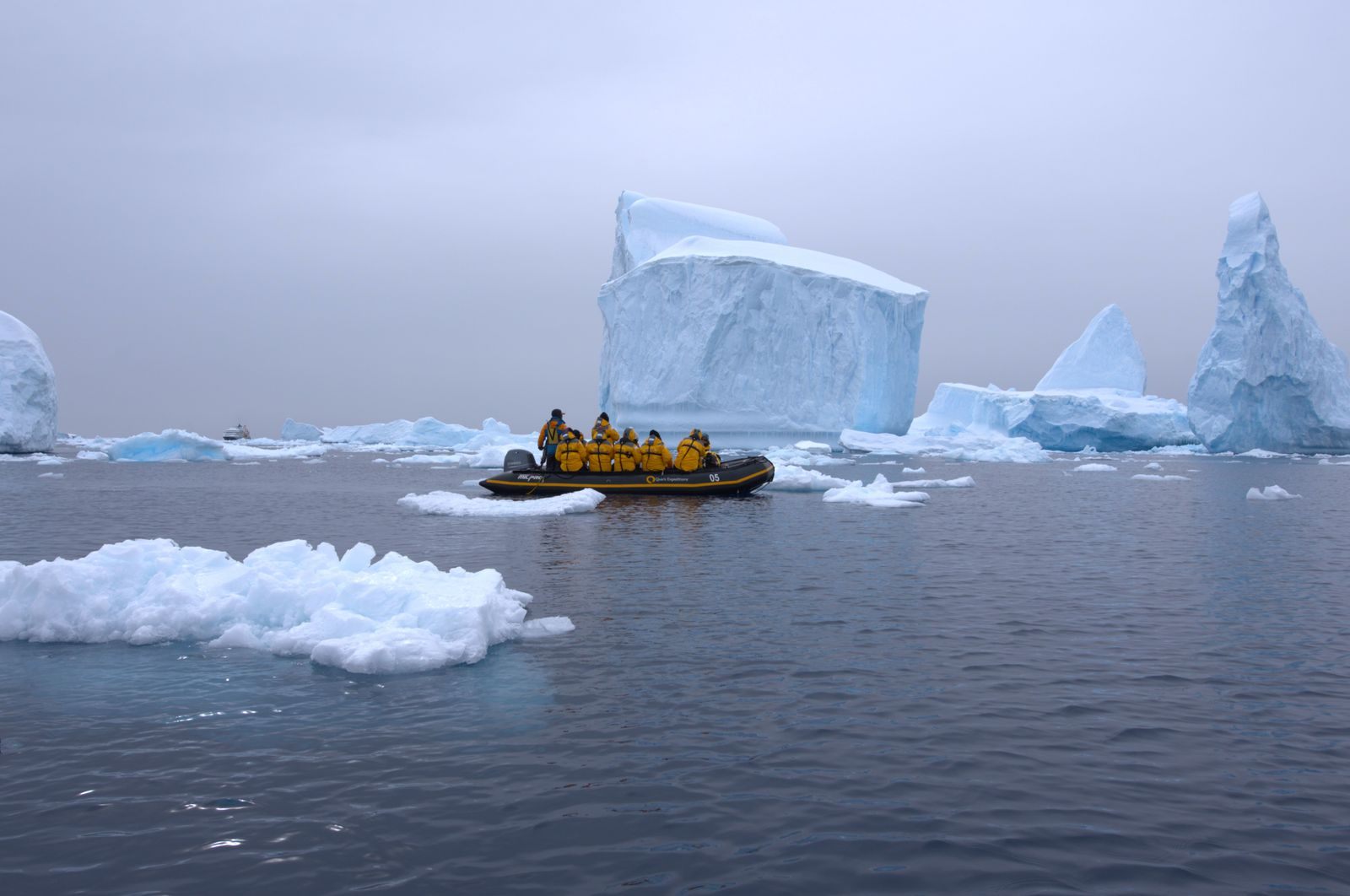 Expedition guests in a small boat among icebergs on an explorer cruise, part of what expedition cruise lines offer