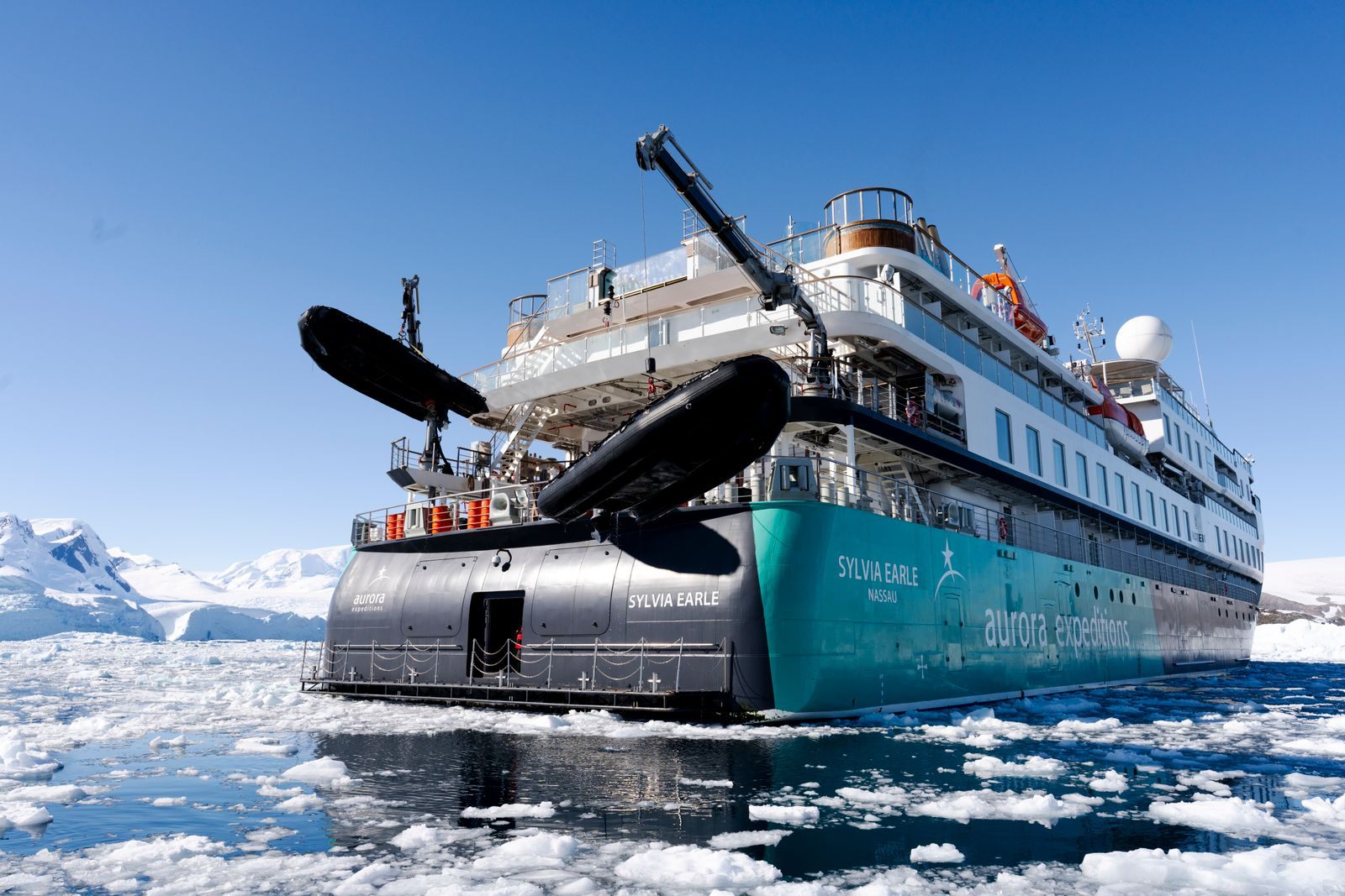 Expedition cruise ship with an inverted bow sailing among floating ice
