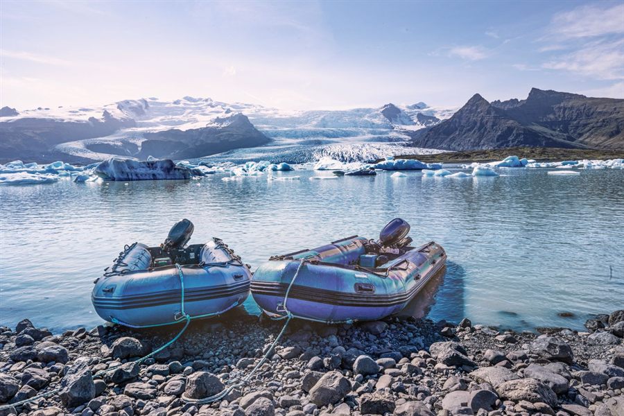 Inflatable boats pulled up on a stony shore with mountains behind